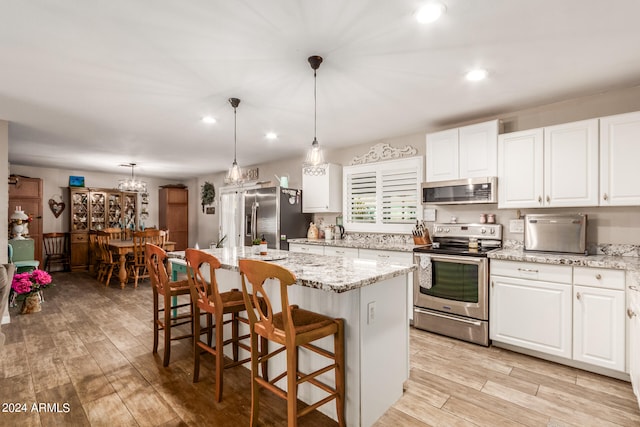 kitchen with white cabinetry, stainless steel appliances, pendant lighting, and a kitchen island