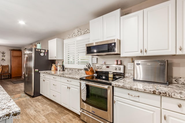 kitchen with light stone countertops, appliances with stainless steel finishes, light hardwood / wood-style flooring, and white cabinetry