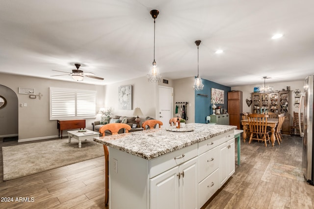 kitchen featuring white cabinets, hardwood / wood-style flooring, a center island, and hanging light fixtures