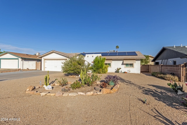 ranch-style home featuring solar panels and a garage