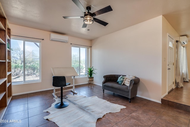 sitting room featuring ceiling fan, plenty of natural light, an AC wall unit, and dark tile patterned floors