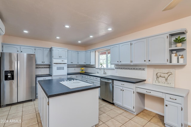 kitchen featuring light tile patterned flooring, sink, appliances with stainless steel finishes, a kitchen island, and white cabinets