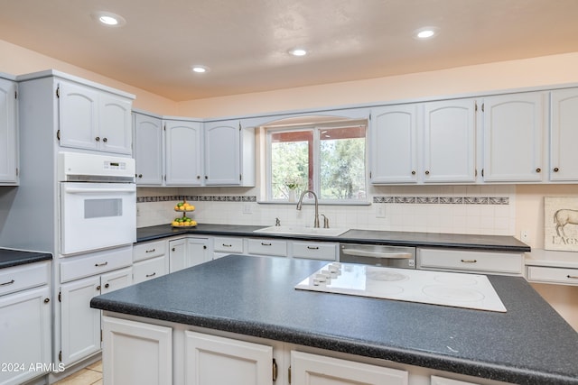 kitchen with white cabinetry, white appliances, sink, and backsplash