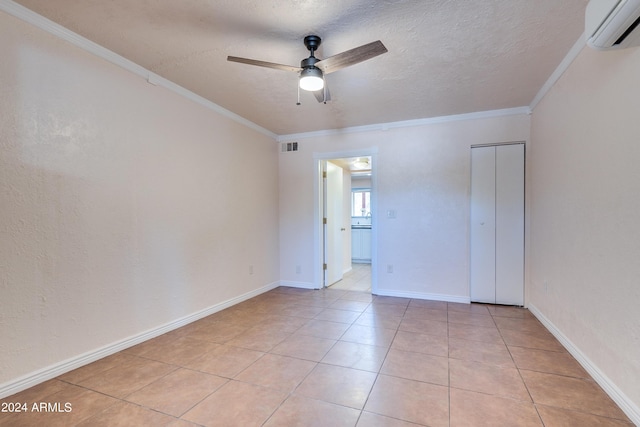 spare room featuring crown molding, ceiling fan, a textured ceiling, light tile patterned flooring, and an AC wall unit