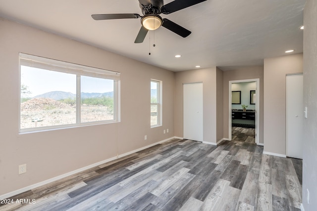 unfurnished bedroom featuring a mountain view, wood-type flooring, a closet, and ceiling fan