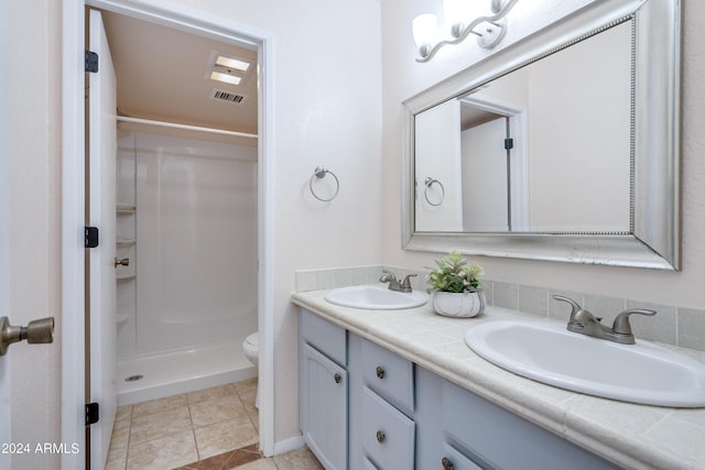 bathroom featuring walk in shower, vanity, toilet, and tile patterned flooring