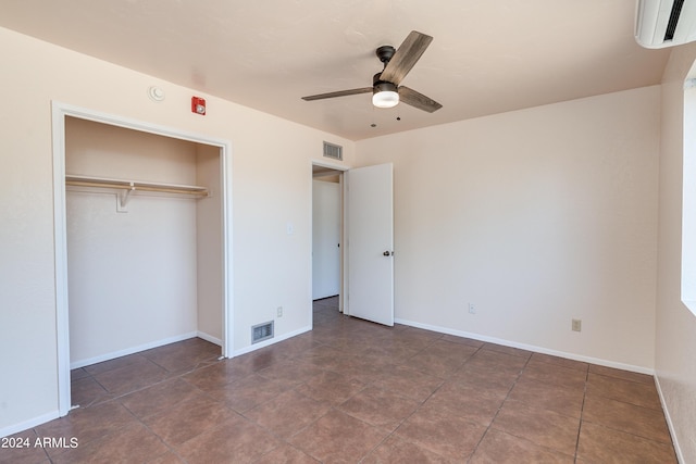 unfurnished bedroom with a wall mounted AC, ceiling fan, and a closet