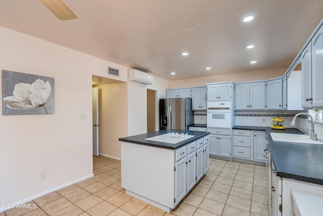 kitchen featuring a kitchen island, a wall mounted air conditioner, sink, stainless steel refrigerator with ice dispenser, and white oven