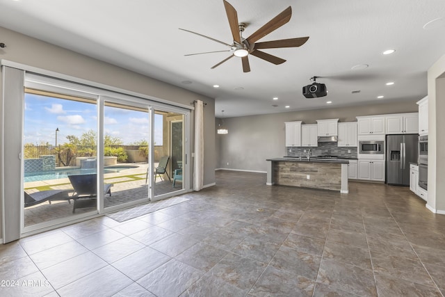kitchen featuring a ceiling fan, white cabinets, under cabinet range hood, stainless steel appliances, and backsplash