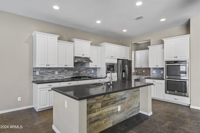 kitchen featuring visible vents, a sink, dark countertops, under cabinet range hood, and stainless steel appliances