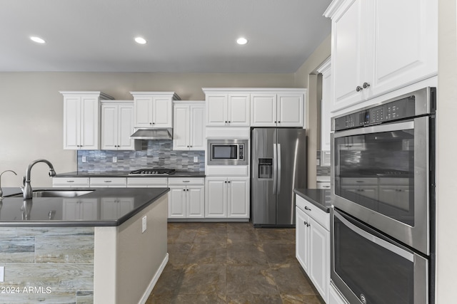 kitchen featuring dark countertops, appliances with stainless steel finishes, a sink, and under cabinet range hood