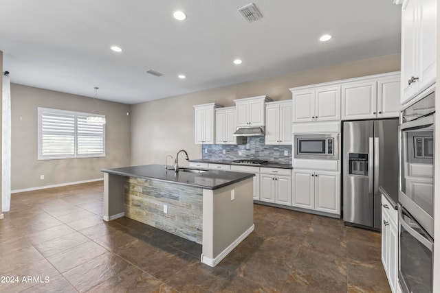 kitchen featuring tasteful backsplash, white cabinets, stainless steel appliances, a kitchen island with sink, and sink