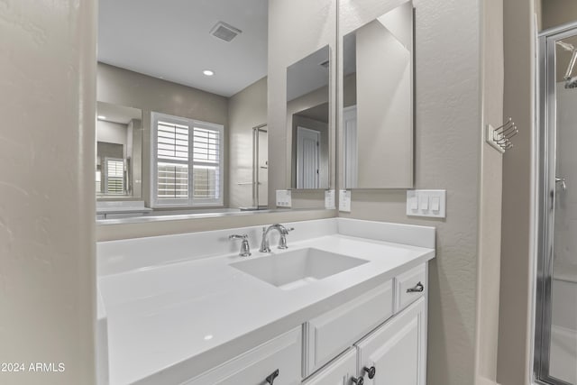 bathroom with visible vents, a textured wall, vanity, and a shower with door