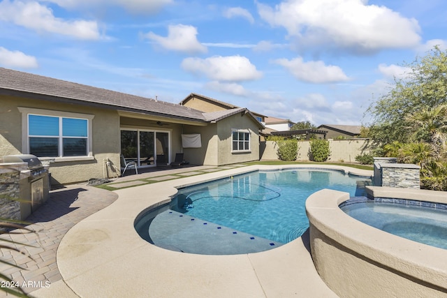 view of swimming pool with exterior kitchen, a grill, a patio area, a pool with connected hot tub, and fence