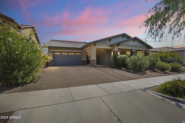 craftsman inspired home featuring driveway, a garage, stone siding, and stucco siding
