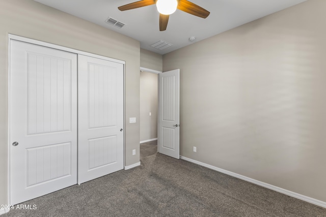 unfurnished bedroom with visible vents, dark colored carpet, a closet, and baseboards