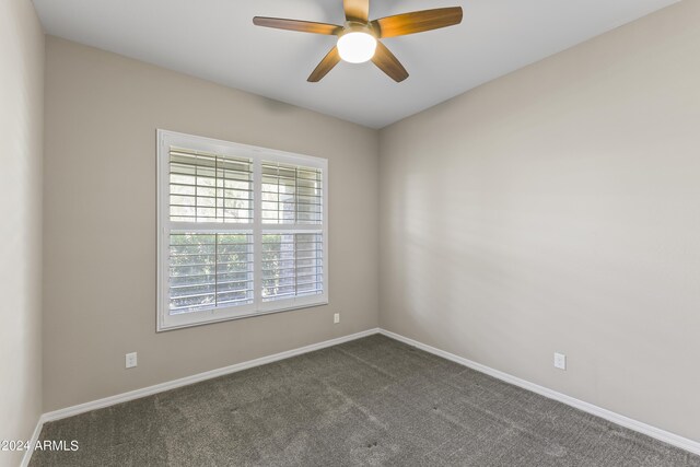 unfurnished room featuring ceiling fan, dark colored carpet, and baseboards