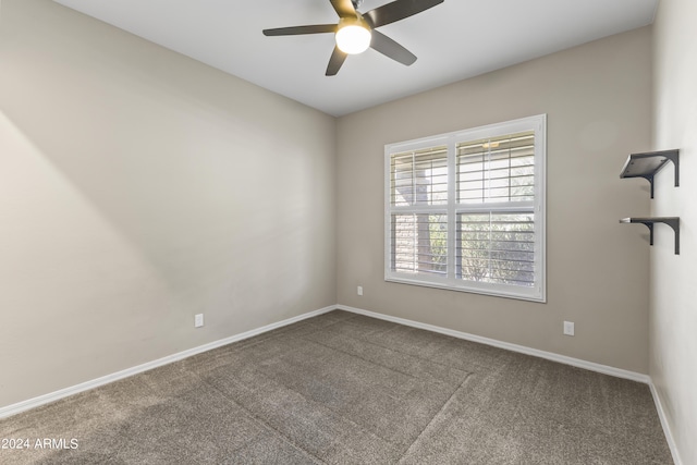 carpeted spare room featuring baseboards and a ceiling fan
