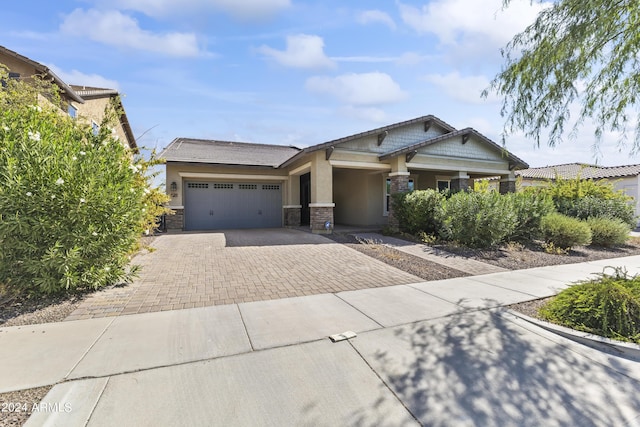 craftsman house featuring stone siding, a garage, decorative driveway, and stucco siding