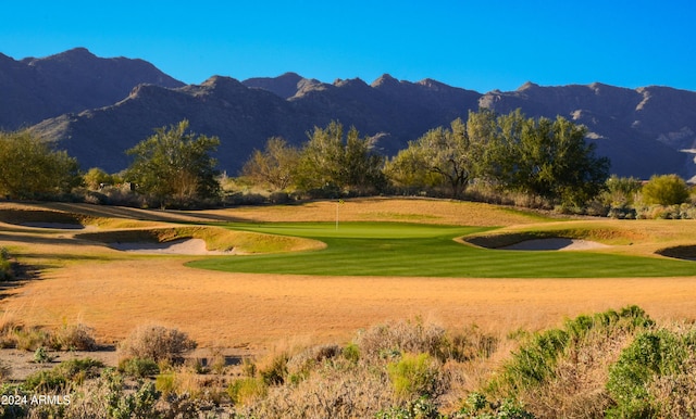 surrounding community with a mountain view, golf course view, and a lawn