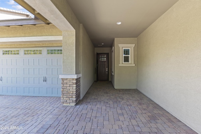 entrance to property featuring a garage, stucco siding, and stone siding