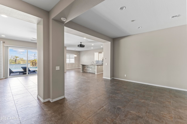 unfurnished living room featuring tile patterned flooring, sink, and a wealth of natural light