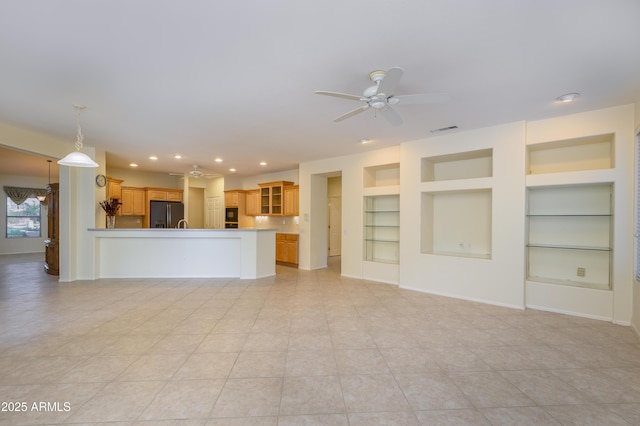 unfurnished living room featuring built in features, a ceiling fan, visible vents, baseboards, and recessed lighting