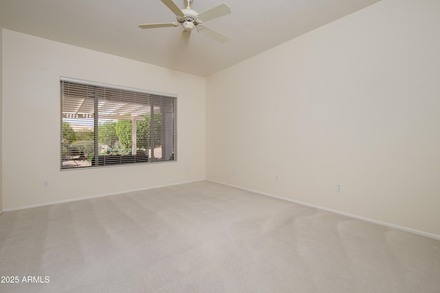 spare room with baseboards, light carpet, and ceiling fan