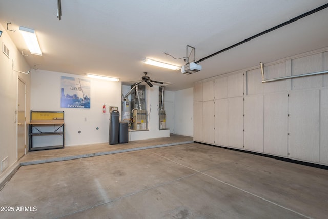 garage featuring water heater, visible vents, and a garage door opener