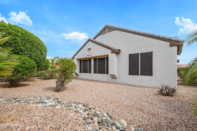 rear view of property with a tile roof and stucco siding