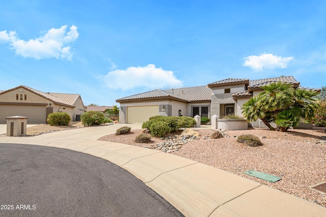 mediterranean / spanish home with stucco siding, a tiled roof, an attached garage, and concrete driveway