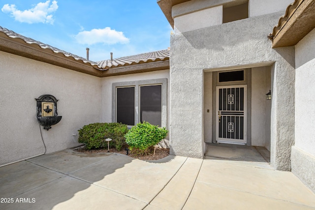 property entrance featuring stucco siding and a tiled roof