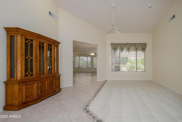 unfurnished room with high vaulted ceiling, a ceiling fan, visible vents, and baseboards