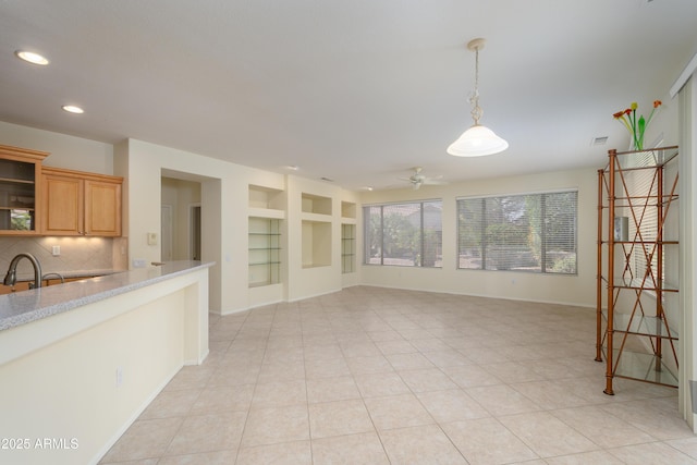 unfurnished living room featuring light tile patterned floors, built in features, a ceiling fan, and a sink