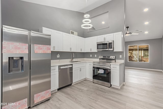 kitchen with sink, white cabinetry, light hardwood / wood-style flooring, appliances with stainless steel finishes, and pendant lighting