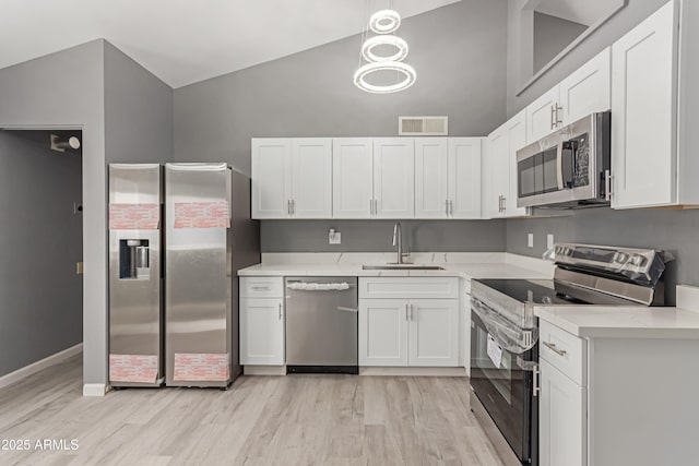 kitchen with white cabinetry, stainless steel appliances, and decorative light fixtures