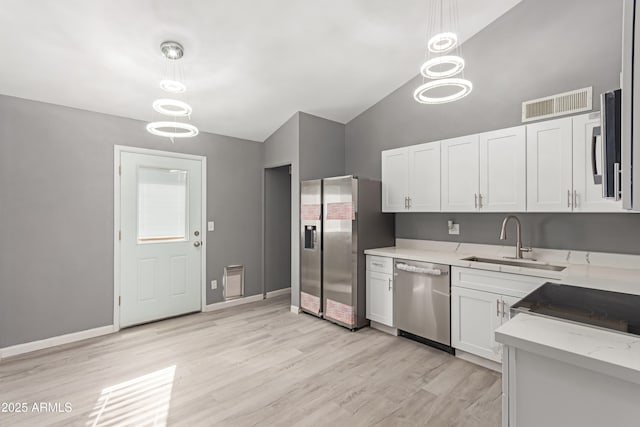 kitchen featuring appliances with stainless steel finishes, white cabinetry, sink, hanging light fixtures, and light stone counters