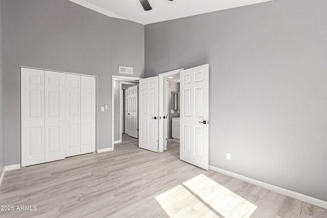 unfurnished bedroom featuring ceiling fan, high vaulted ceiling, a closet, and light wood-type flooring