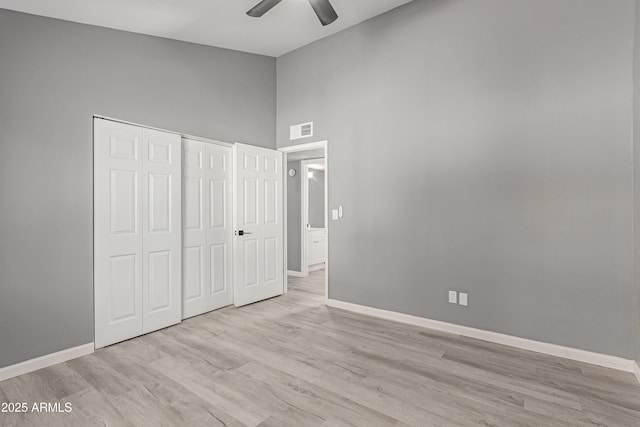 unfurnished bedroom featuring high vaulted ceiling, light hardwood / wood-style floors, a closet, and ceiling fan