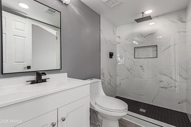 bathroom with a tile shower, vanity, and toilet