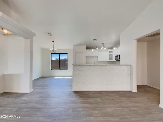 kitchen featuring white cabinetry, rail lighting, sink, a notable chandelier, and hardwood / wood-style flooring