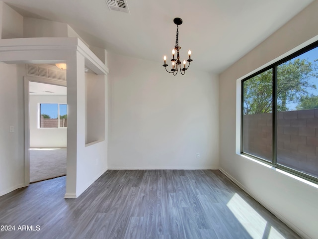 unfurnished room with hardwood / wood-style flooring, a notable chandelier, and lofted ceiling