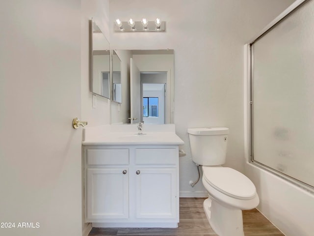 full bathroom with combined bath / shower with glass door, toilet, vanity, and wood-type flooring