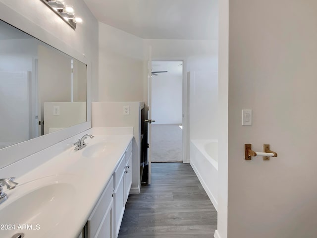 bathroom with a tub, vanity, and wood-type flooring