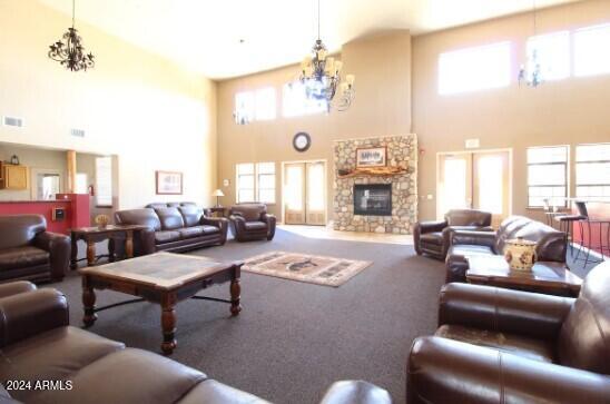 living room featuring a high ceiling, a stone fireplace, carpet floors, and a healthy amount of sunlight