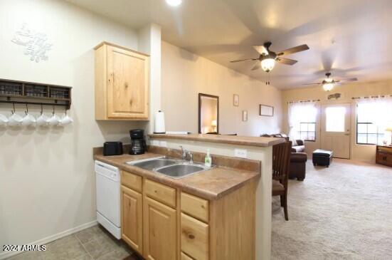 kitchen featuring light carpet, white dishwasher, sink, light brown cabinetry, and ceiling fan