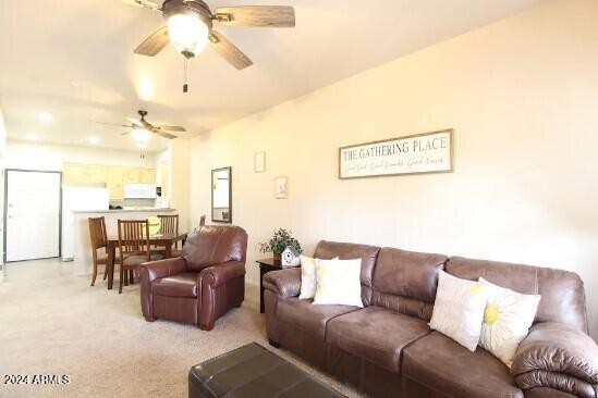 living room with light colored carpet and ceiling fan