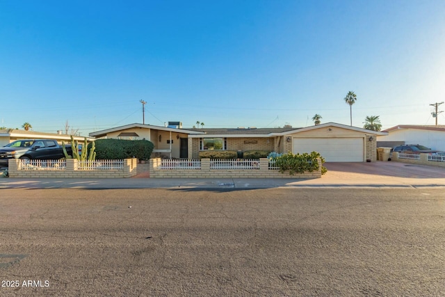 ranch-style house with a fenced front yard, concrete driveway, and brick siding