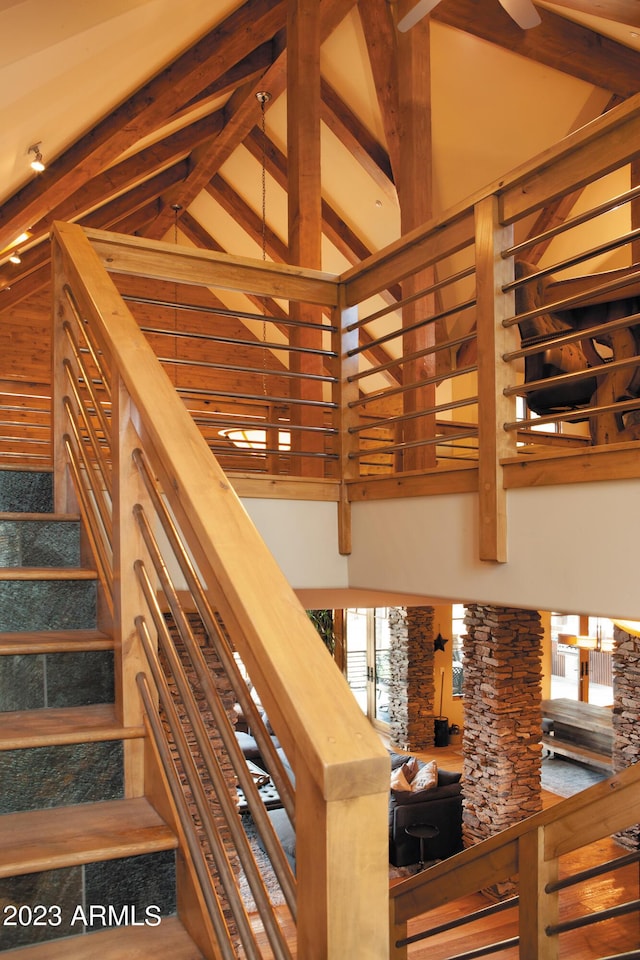 stairs featuring beam ceiling and high vaulted ceiling