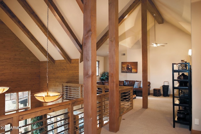 hallway featuring light carpet, high vaulted ceiling, beamed ceiling, and wood walls